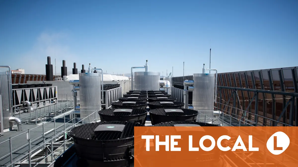 A rooftop with industrial cooling fans and ventilation units next to an orange logo for The Local.