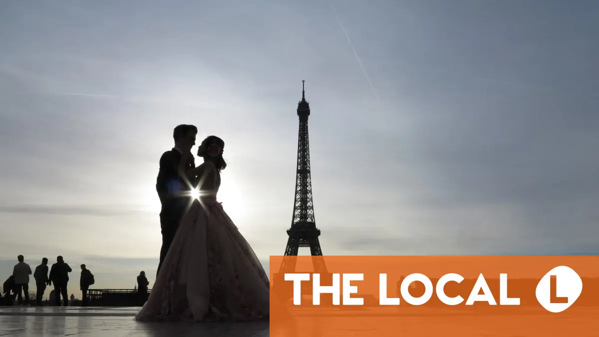 A couple stands in front of the Eiffel Tower at sunset.
