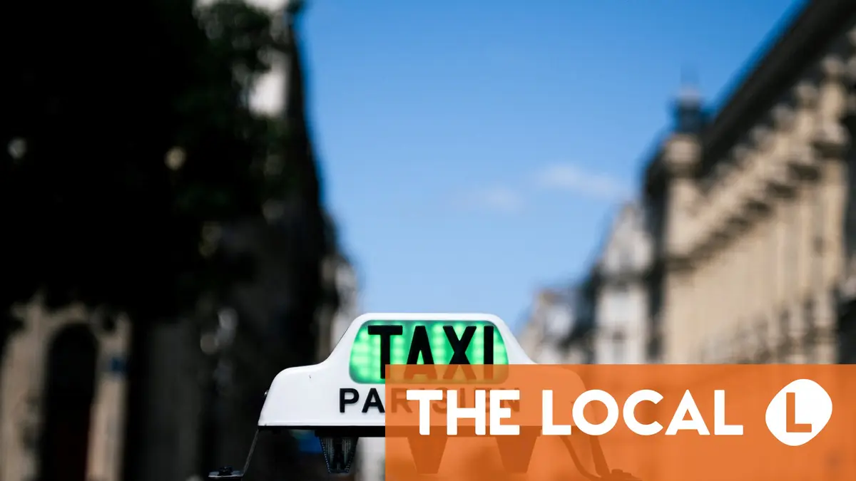 A taxi roof sign with a green light and an orange banner reading 'THE LOCAL'.