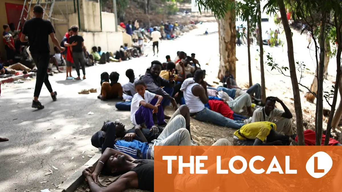 A large group of people gathered outdoors, many lying on the ground.