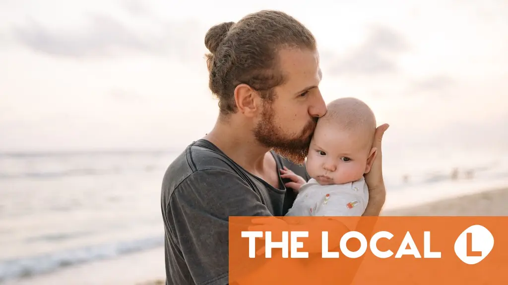 A father kissing his baby on the beach with a news logo overlay.